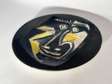 a black plate with a painting on it sitting on a table