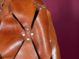 a close up of a brown leather bag with rivets on it