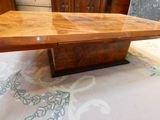 une grande table en bois avec un plateau en verre, posée sur un tapis