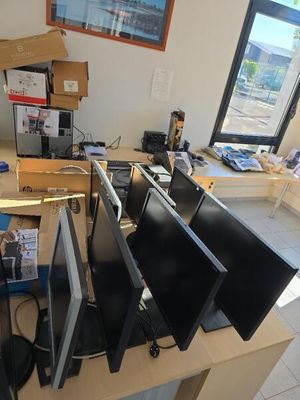 Plusieurs écrans d'ordinateur sont posés sur un bureau devant une fenêtre.