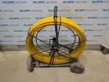an image of a yellow hose is on a cart in front of a wall