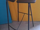un tabouret noir posé devant un mur jaune et bleu