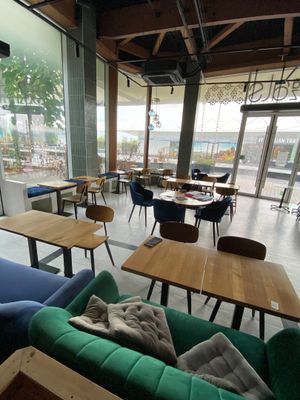 many tables and couches in a restaurant with a view of the water