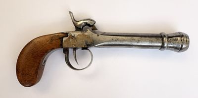 un vieux pistolet avec une poignée en bois sur une surface blanche