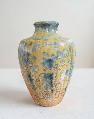 un vase jaune et bleu posé sur une table blanche