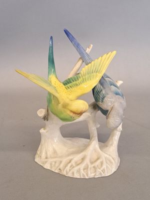 two figurines of birds sitting on a tree branch