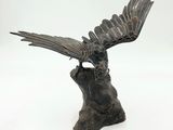 statue of a bird perched on a tree stump with a white background