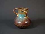 a brown and blue vase sitting on a black surface