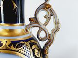 a blue vase with a gold trim and a pink flower