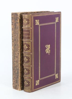 un vieux livre posé sur une table blanche, à côté d'un livre violet