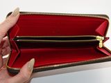 someone is holding a red and black wallet with a gold zipper