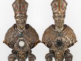 two statues of a man and a woman with hats on their heads