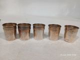 quatre tasses en argent sont alignées sur une surface blanche