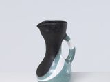 un vase noir et bleu posé sur une table blanche