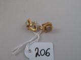 une étiquette posée sur une table blanche, avec une paire de boucles d'oreilles en or