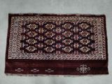 un tapis oriental posé sur un sol blanc, bordé d'une frange marron