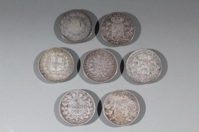 six pièces d'argent sont disposées en triangle sur une surface blanche