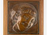 un gros plan sur une plaque en bronze représentant le visage d'un homme