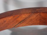 a close up of a wooden chair with a curved seat