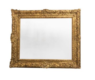 un grand miroir à cadre doré, orné d'un motif décoratif sur fond blanc