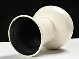 a white vase sitting on a table with a black background