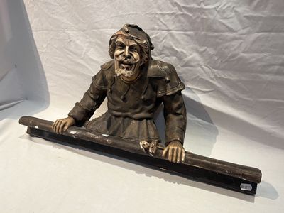 une statue représentant un homme assis sur une longue planche de bois