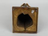 an antique bronze figurine of a bird in a square hole