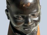 sculpture of a young boy ' s head on a wooden base