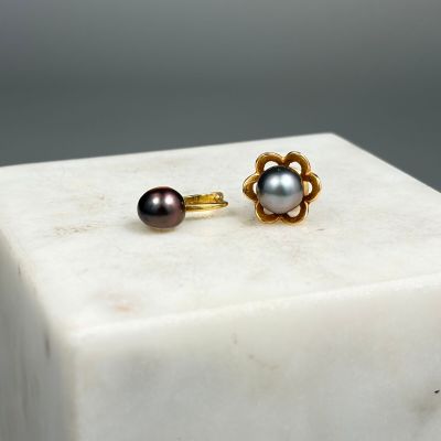 paire de boucles d'oreilles à clous en forme de fleur, en perles et or, posées sur un bloc de marbre