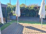 a wooden deck with umbrellas on it and a bench in the background