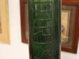 someone is holding a green glass bottle with the word beer written on it