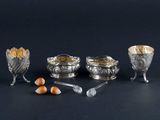 four silver dishes and spoons on a black surface