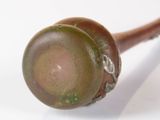 a close up of a wooden stick with a green ball on it