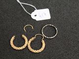 two pairs of gold hoop earrings on a black surface with a price tag