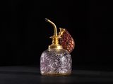 un flacon de parfum à l'ancienne orné d'une fleur rouge sur le bouchon