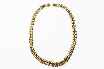 gros plan d'un collier en chaîne en or sur fond blanc
