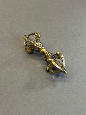 un petit objet métallique posé sur une table, dans lequel est enfoncé un couteau