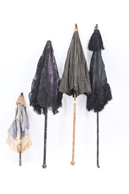 three umbrellas are lined up against a white wall with black lace