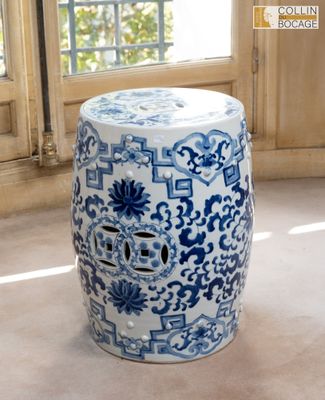 un tabouret bleu et blanc posé devant une fenêtre