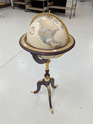 un vieux globe terrestre posé sur un trépied dans une pièce