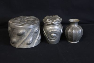 three silver vases sitting next to each other on a black background