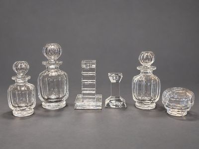 Plusieurs objets en verre sont disposés sur une table devant un fond gris.