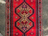 a red and blue rug sitting on top of a cement floor