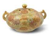 a gold and red vase with a lid on a white surface