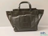 the small grey bag is sitting on a white surface