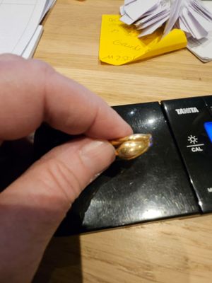 une personne tenant une bague en or posée sur un balancier