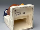 a small ceramic figurine of a couch with a pillow on it