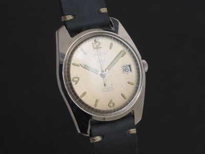 une vieille montre avec un bracelet en cuir noir sur fond noir