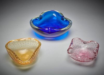 trois bols en verre de couleurs différentes posés sur une surface blanche