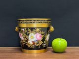 a green apple sitting next to a black and gold vase